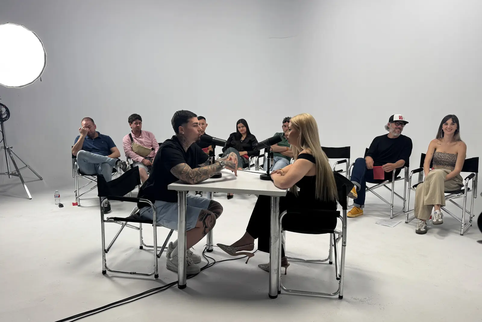 Plató blanco con ocho trabajadores, mesa y micrófonos