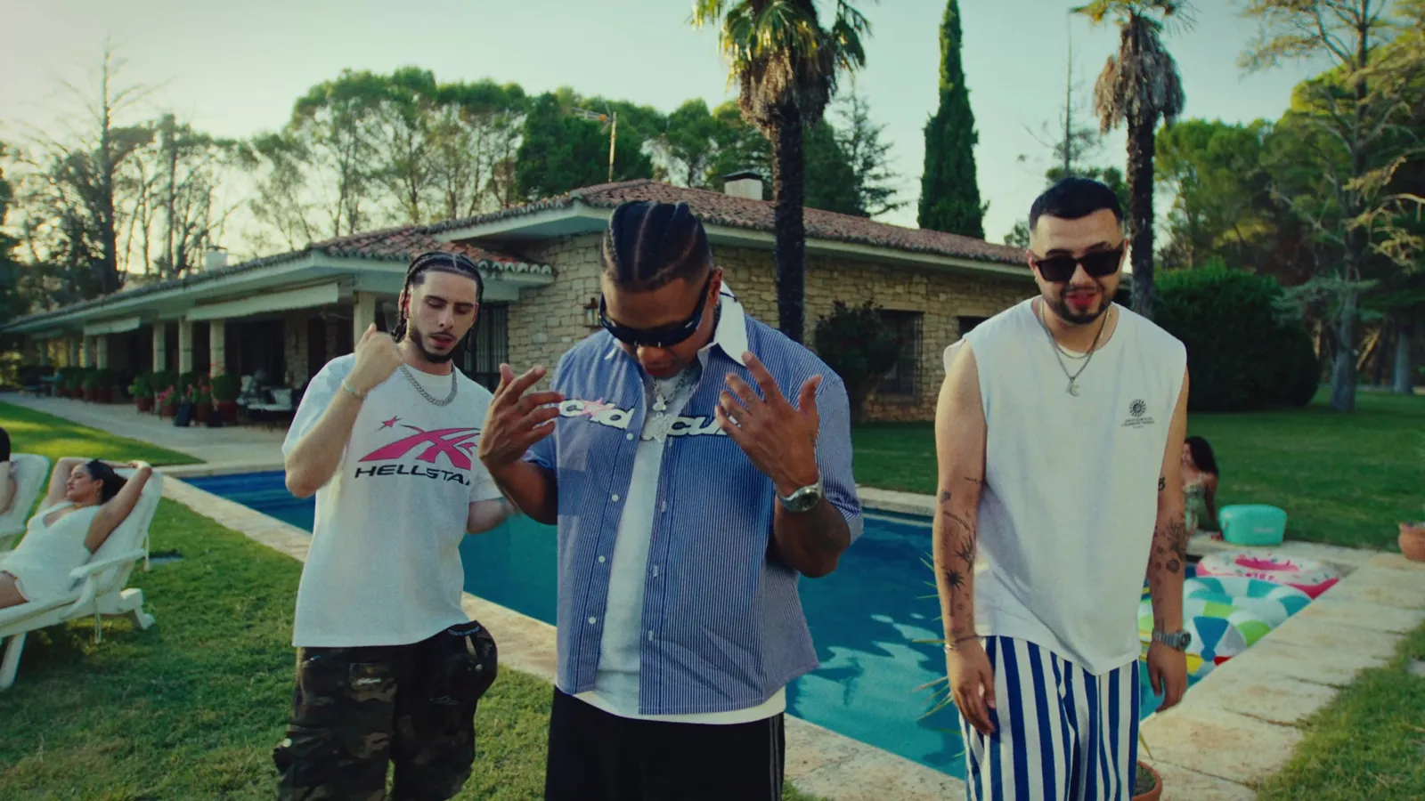 Tres artistas junto a una piscina en el videoclip Bandolerita