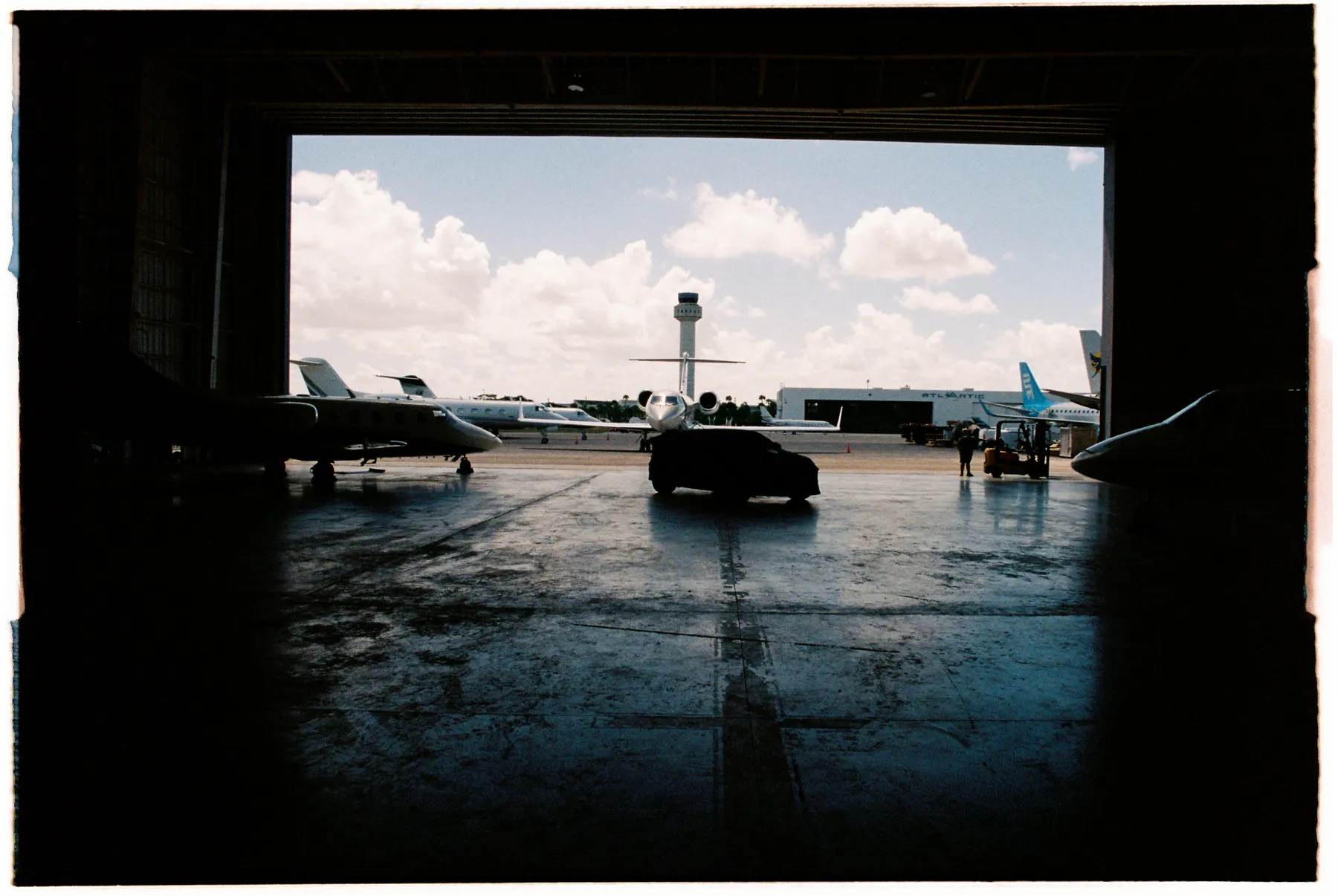 Hangar de jets privados en Miami con el Urus cubierto, en analógico